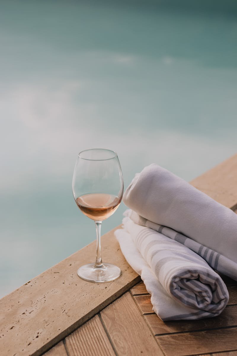 A serene poolside setting featuring a glass of wine and folded towels, exuding summer relaxation vibes.