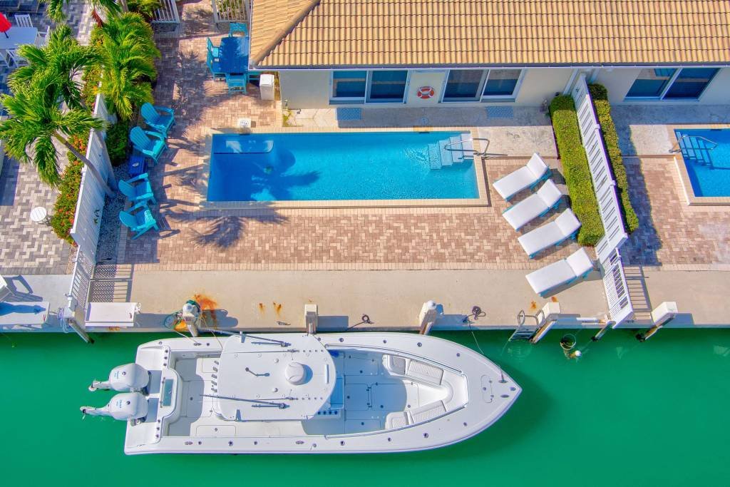 Aerial view of luxury boat docked near poolside vacation home