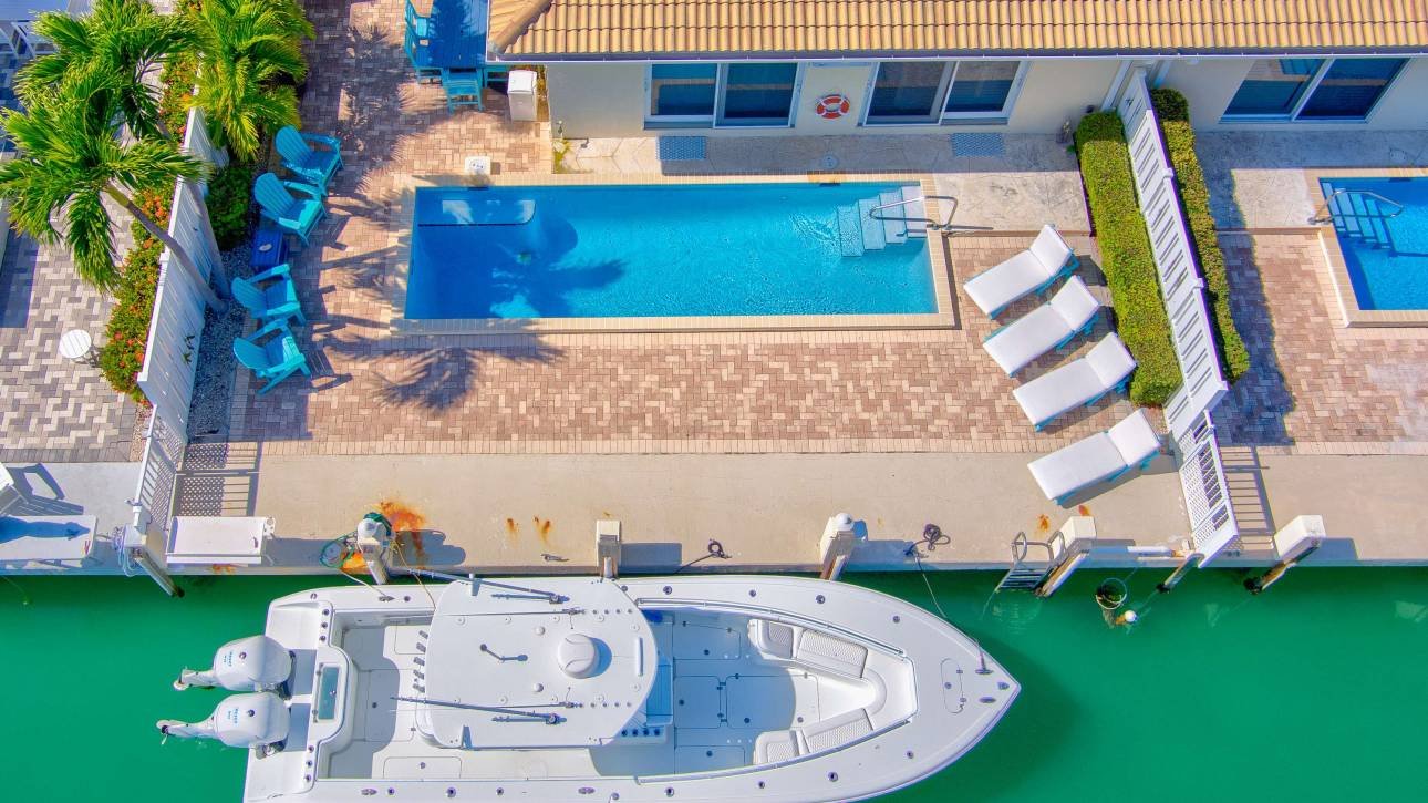 Aerial view of luxury boat docked near poolside vacation home