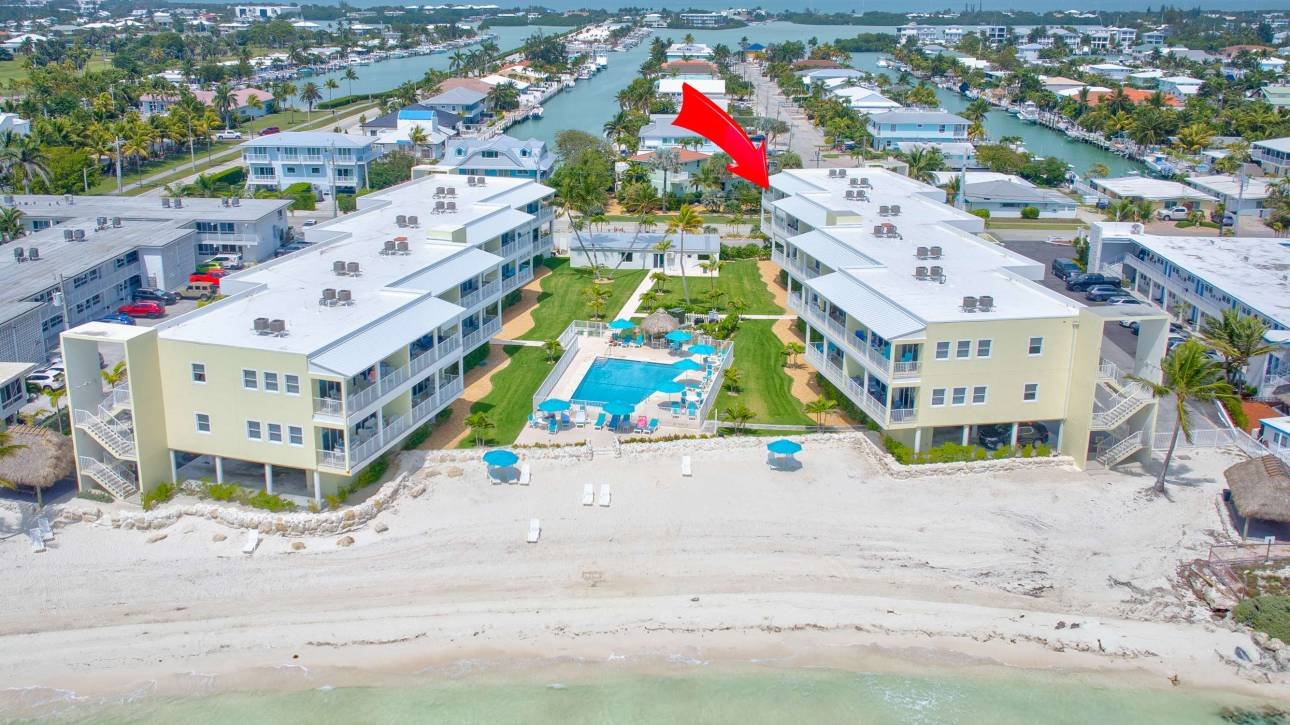 Aerial view of waterfront resort with pool and beach access