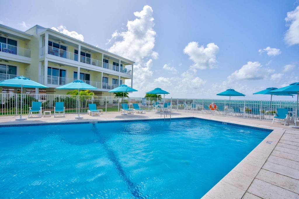 Beachfront condo with pool and sun umbrellas in sunny weather