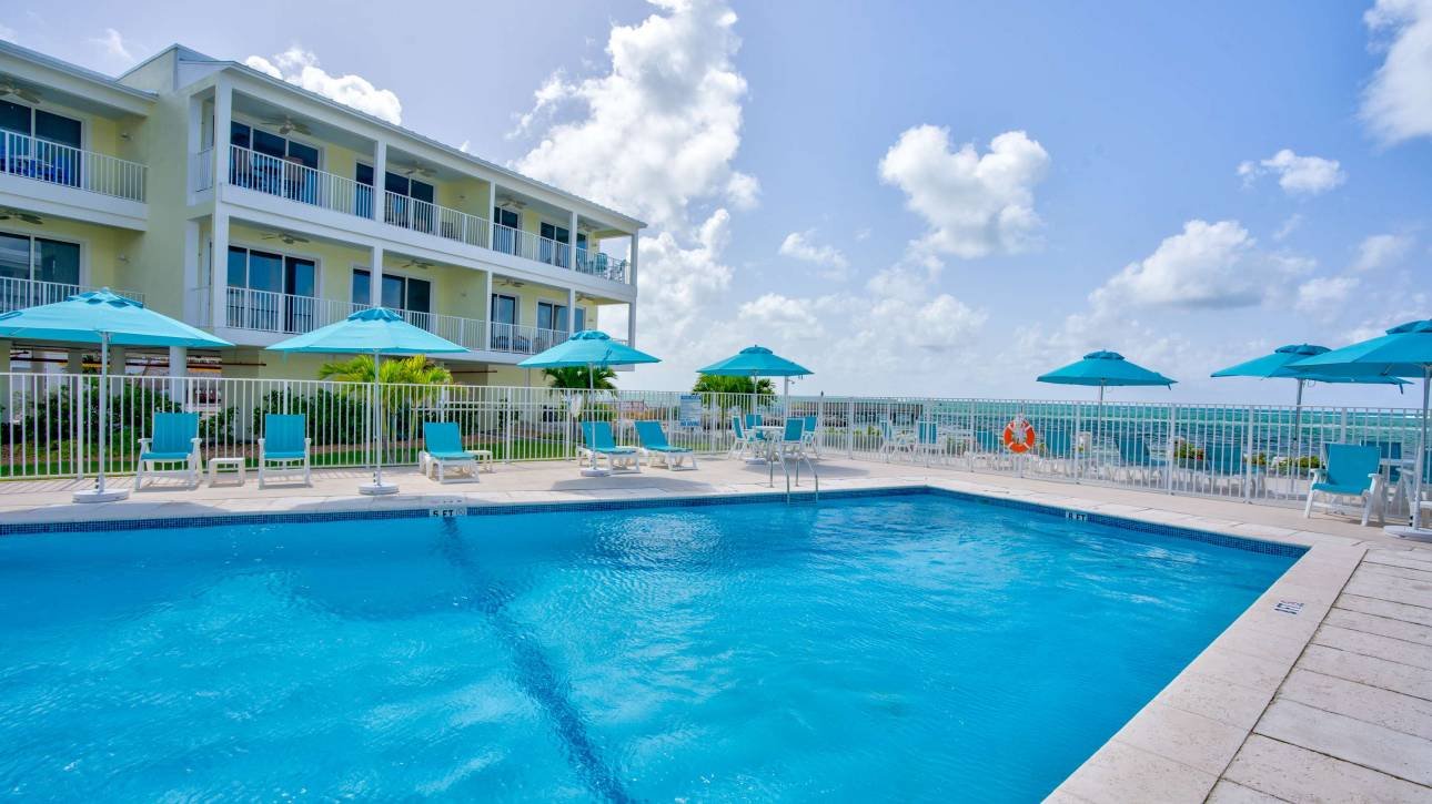 Beachfront condo with pool and sun umbrellas in sunny weather