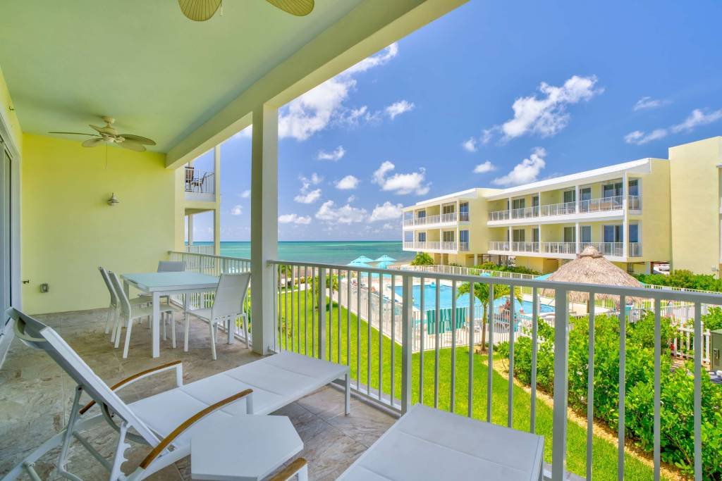 Balcony view of tropical resort with pool and ocean scenery