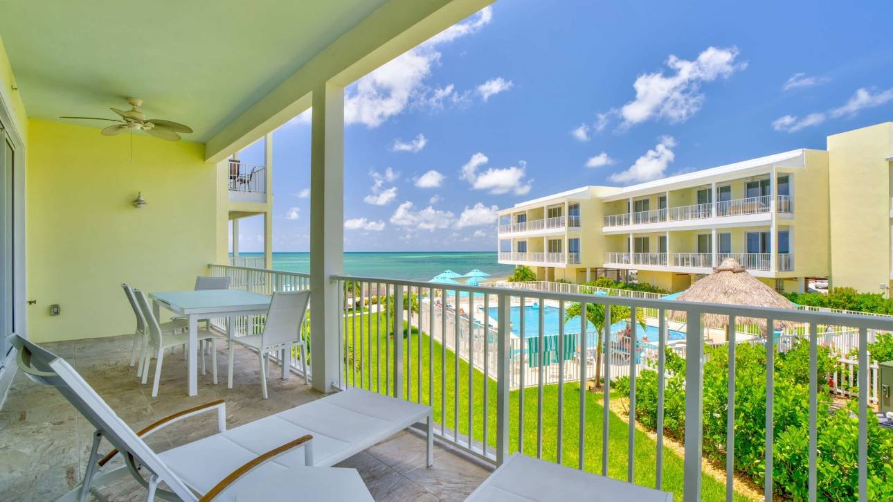 Balcony view of tropical resort with pool and ocean scenery