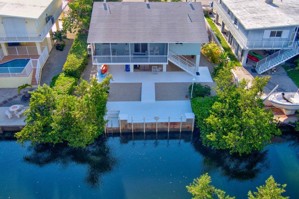 Aerial view of waterfront house with large deck and lush greenery