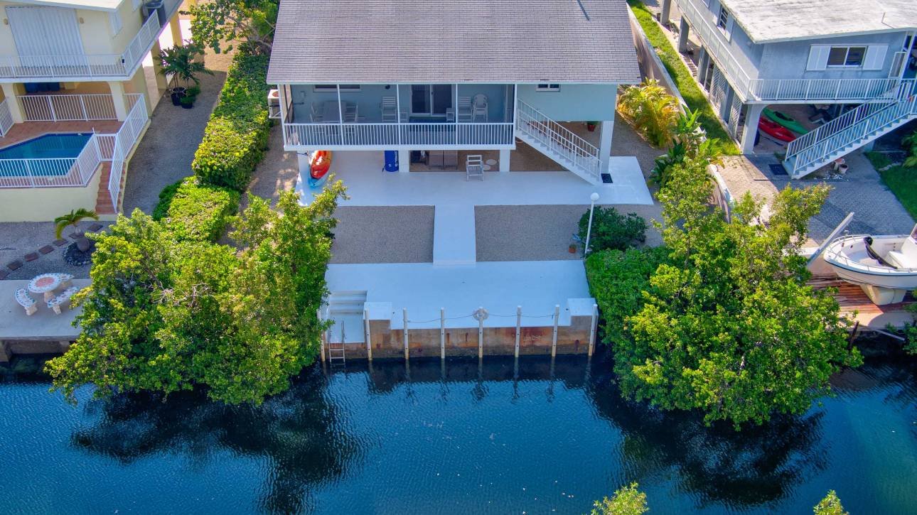 Aerial view of waterfront house with large deck and lush greenery