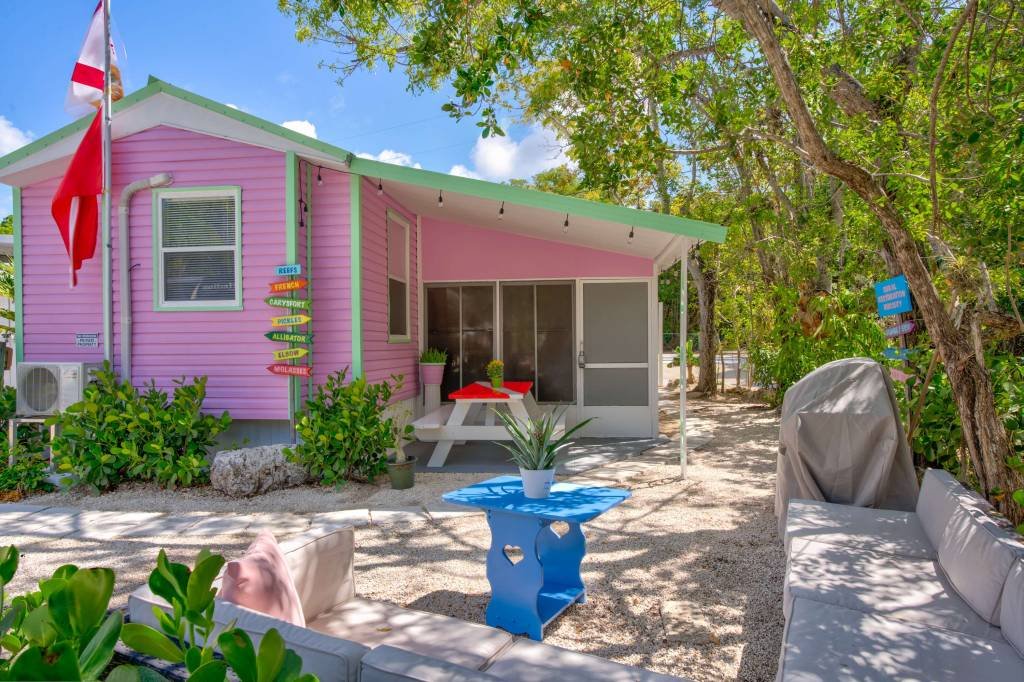 Charming pink beach house with outdoor seating and greenery
