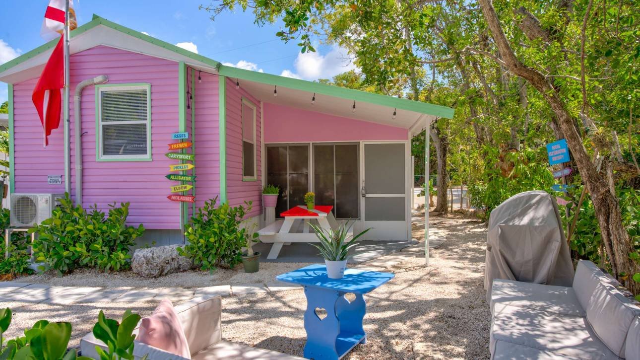 Charming pink beach house with outdoor seating and greenery