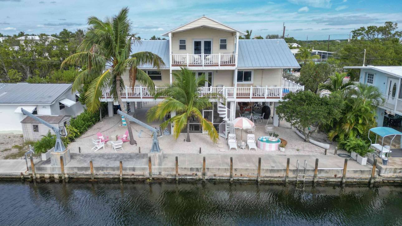 Waterfront house with palm trees and outdoor seating area